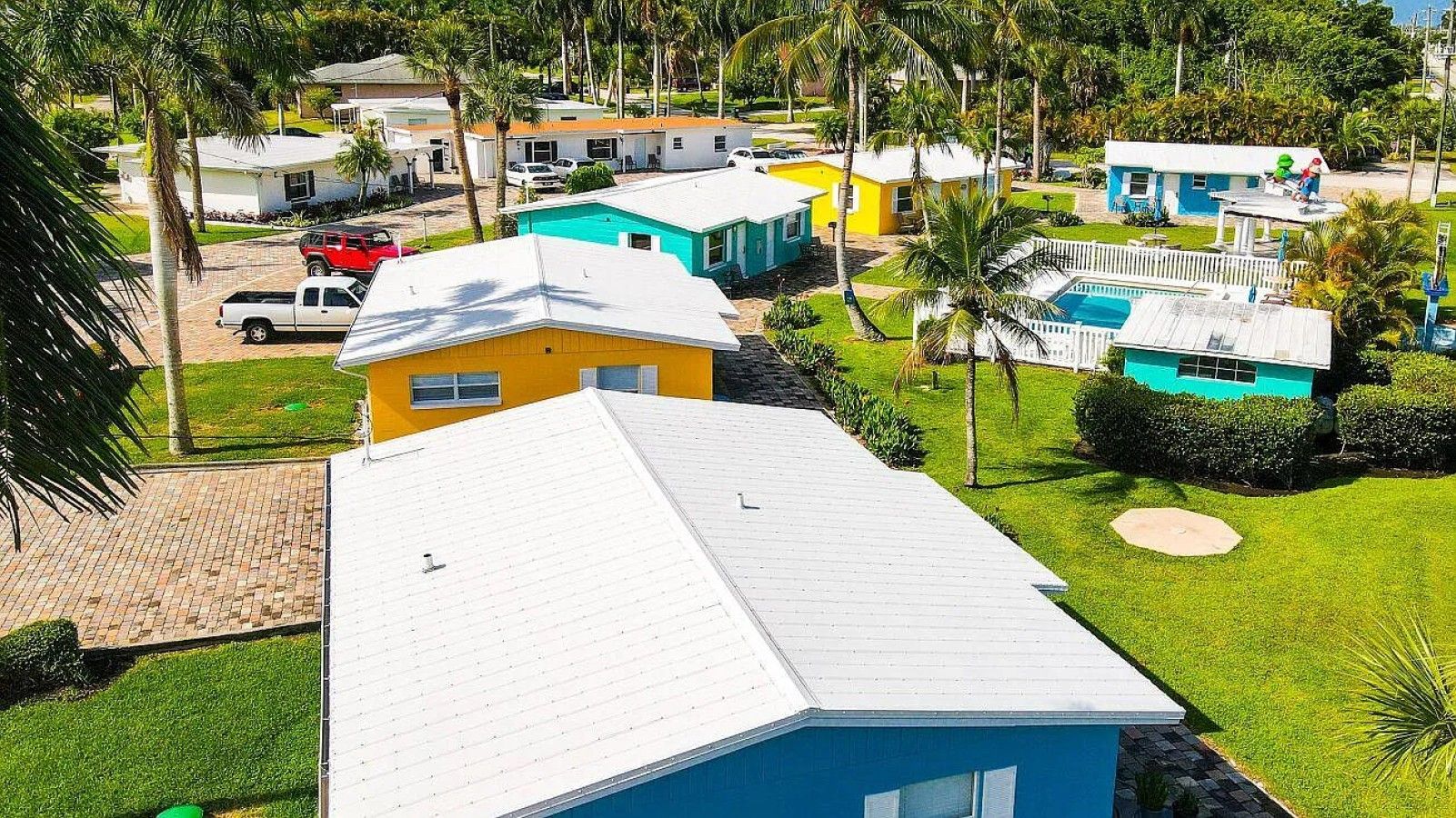 Zona residencial amb cases multicolores, una piscina i un jardí ben cuidat.