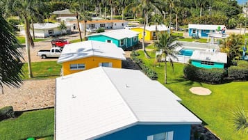 Zona residencial amb cases multicolores, una piscina i un jardí ben cuidat.