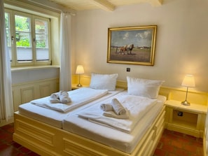 A hotel room with two beds, a painting on the wall, and a window with curtains. - Holiday Apartment in Sylt With 1 Bedroom (Sylt)