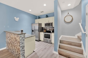 A modern kitchen with a central island, stainless steel appliances, and a wooden staircase. - Relaxing 3 BD/ 2 BA/ West Lucaya - 3204 GL (Kissimmee)