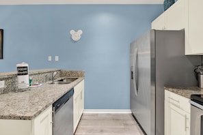 A kitchen with a granite countertop, stainless steel appliances, and a blue wall. - Relaxing 3 BD/ 2 BA/ West Lucaya - 3204 GL (Kissimmee)