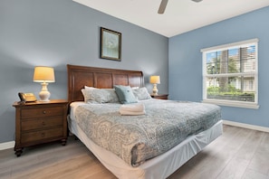 A bedroom with a bed, two bedside tables with lamps, a wooden headboard, a window with blinds, and a ceiling fan. - Relaxing 3 BD/ 2 BA/ West Lucaya - 3204 GL (Kissimmee)