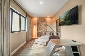 Une chambre à coucher de taille modeste, comprenant un lit, un bureau, une chaise, une carte accrochée au mur et un tableau.