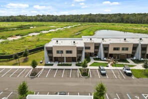 Un bâtiment moderne doté d’un parking, entouré de verdure et bordé par un plan d’eau.