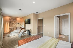 Une chambre à coucher comprenant un lit, un bureau, une chaise, une carte accrochée au mur et une porte donnant sur une autre pièce.