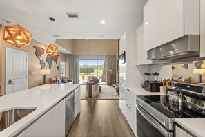 A modern kitchen with a central island, stainless steel appliances, and a view to the outdoors. - Pininfarina Masterpiece 4 BD/4.5 BA - 5534 PW (Kissimmee)