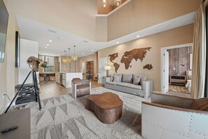A spacious living area with a large sofa, a coffee table, and a world map on the wall. - Modern Oasis 4 BD/4.5 BA Magic Village by Pininfarina - 5501 TR (Kissimmee)