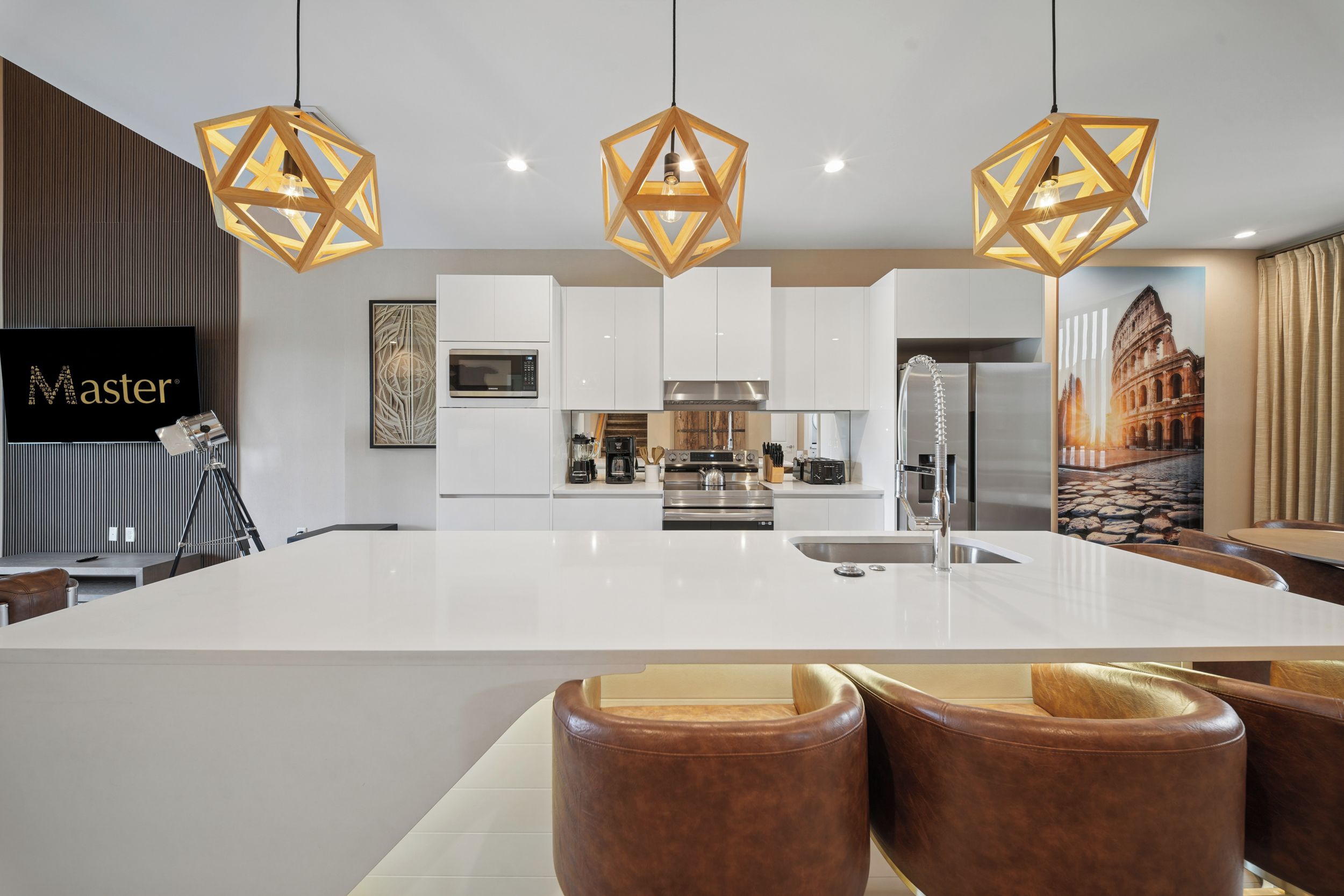 A modern kitchen with a central island, white cabinetry, and pendant lighting.