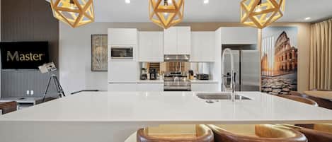 A modern kitchen with a central island, white cabinetry, and pendant lighting.