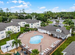 A residential area with multiple houses, a swimming pool, and a fenced patio area with lounge chairs. - 3 BD/ 2 BA/ The Villas at Laguna Bay (5017-95 LB) (Kissimmee)