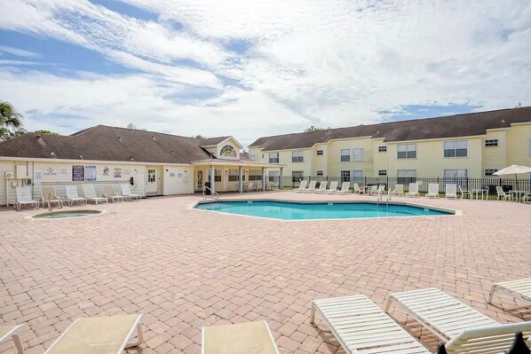 A hotel courtyard with a swimming pool, lounge chairs, and a covered seating area. - 3 BD/ 2 BA/ The Villas at Laguna Bay (5017-95 LB) (Kissimmee)