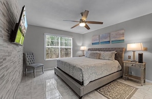 A bedroom with a bed, a chair, a ceiling fan, a window, and artwork on the wall. - 3 BD/ 2 BA/ The Villas at Laguna Bay (5017-95 LB) (Kissimmee)