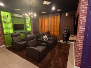 A living room with a fireplace, a television, and a green shelving unit. - 5 BD/ 5.5 BA/ Windsor Cay - 16007 CC (Clermont)