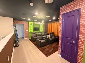 A living room with a fireplace, leather sofas, and a purple door. - 5 BD/ 5.5 BA/ Windsor Cay - 16007 CC (Clermont)