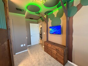 A hallway with a wooden dresser, a flat-screen TV mounted on the wall, and a ceiling with a tree-like design. - 5 BD/ 5.5 BA/ Windsor Cay - 16007 CC (Clermont)