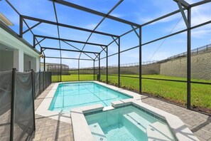 Une piscine dotée d’une zone couverte, entourée d’une clôture et d’un mur en pierre.