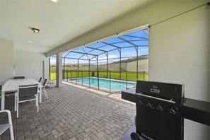 An outdoor patio with a grill, a pool, and a view of the countryside. - 8 BD/ 6 BA/ Windsor Island - 2290 LC (Davenport)