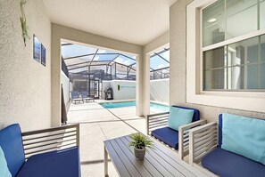 A covered outdoor seating area with a pool in the background. - 4 BD/ 3 BA/ Storey Lake - 4816 ML (Kissimmee)