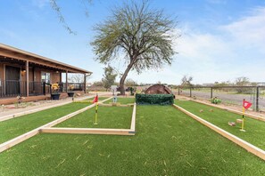 A well-maintained outdoor area with artificial grass, a wooden structure, and a large tree. - Wild West Town and Ranch Casita; 7 min. from Arizona Athletic Grounds AAG (Mesa)