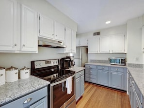 A kitchen with white cabinets, a stove, a microwave, and a coffee maker. - Blue Ridge Mountain Retreat Overlooking the 18th Hole (Wintergreen Resort)