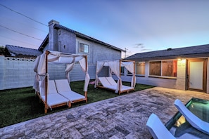 A backyard with two canopy beds, a swimming pool, and a house with a tiled roof. - Scottsdale Retreat•Heated Pool•Sleeps 10 •Old Town (Scottsdale)