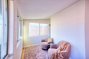 A room with a large window, a brick wall, a patterned rug, and two chairs. - Scottsdale Retreat•Heated Pool•Sleeps 10 •Old Town (Scottsdale)