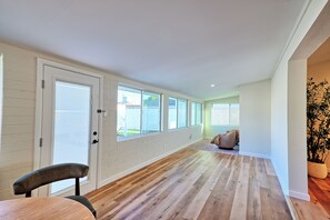 Un couloir doté d’un plancher en bois, de murs blancs et de grandes fenêtres.