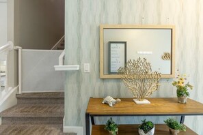 A staircase leading to a landing with a wooden table displaying decorative items and a framed piece of art. - Immersive 5 BD/ 4.5 BA/ Solara Resort - 1592 CP (Kissimmee)