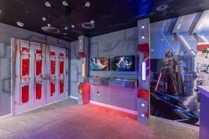 A room with a red carpet, a wall-mounted TV, and a Darth Vader statue. - Immersive 5 BD/ 4.5 BA/ Solara Resort - 1592 CP (Kissimmee)