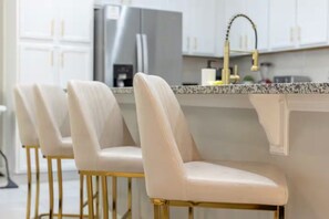 A modern kitchen with white cabinets, a stainless steel refrigerator, and a gold faucet. - Immersive 5 BD/ 4.5 BA/ Solara Resort - 1592 CP (Kissimmee)