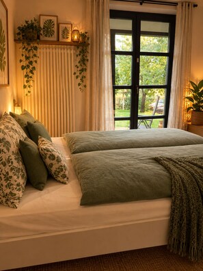 A bedroom with a bed, pillows, a window with curtains, and a view of greenery outside. - New Listing (Welschneudorf)