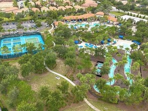 Vue aérienne d’un complexe hôtelier doté d’une piscine, d’un court de tennis et d’un toboggan aquatique.