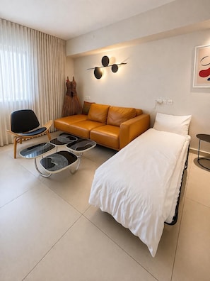A modern hotel room with a sofa, a bed, a chair, and a small table. - סוויטה מרווחת  וממוזגת מיקום מנצח 5דקות הליכה מהים במתחם בריכת שחייה 
sea said92 (Eilat)