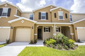 A two-story residential building with a beige facade, black shutters, and a central entrance. - Cozy 4 BD/ 3.5 BA/ Compass Bay - 5149 AD (Kissimmee)