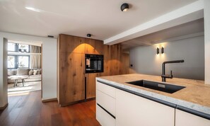 A modern kitchen with a built-in oven, a sink with a contemporary faucet, and wooden cabinetry. - WARM ALPINE CHARM MEETS MODERN COMFORT IN THIS CENTRAL RETREAT (Zermatt)