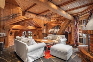 A log cabin interior with a wooden ceiling, a sofa set, a dining table, and a fireplace. - TH689 Log cabin by the Libakken lift, Sleeps 12 (Trysil)