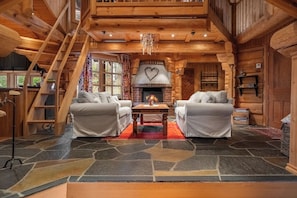 A log cabin interior with a fireplace, two sofas, a wooden staircase, and a stone floor. - TH689 Log cabin by the Libakken lift, Sleeps 12 (Trysil)