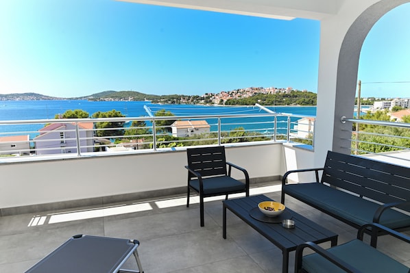 A balcony with a view of the sea, a table with a bowl, and two chairs. - Lity Apartment Green (Podglavica)