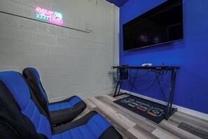 A room with a gaming chair, a treadmill, and a neon sign on the wall. - Family Fun, 5BR with Pool, Games & Themed Rooms (Kissimmee)