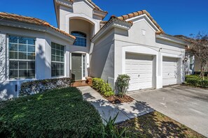 A two-story house with a garage, a front door, and a small garden. - Family Fun, 5BR with Pool, Games & Themed Rooms (Kissimmee)