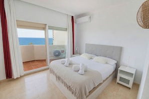 A hotel room with a bed, a nightstand, a wall-mounted air conditioner, and a view of the sea through a sliding glass door. - New Listing (Benalmádena)
