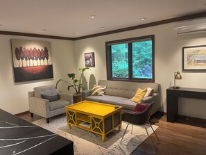 Ein modernes Wohnzimmer mit einer Couch, Sesseln, einem Couchtisch und einem Kamin.