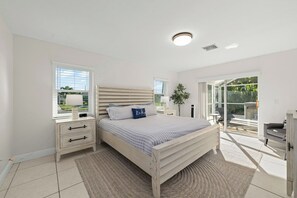 Une chambre à coucher avec un lit, des tables de chevet, une commode, une fenêtre et une vue sur l’extérieur.