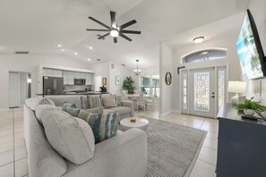 A modern living room with a sofa, coffee table, and a TV. - The Perfect 3BR Villa | Beautiful Lanai and Luxury (Cape Coral)
