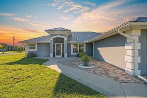 Une maison moderne avec une entrée à l’avant, une allée et une pelouse aménagée.