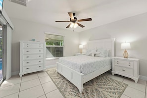 A bedroom with a bed, nightstands, a dresser, a ceiling fan, and a window with blinds. - The Perfect 3BR Villa | Beautiful Lanai and Luxury (Cape Coral)