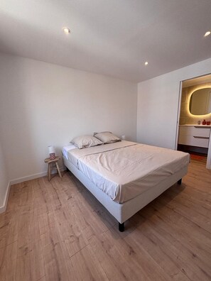 A minimalist bedroom with a single bed, a small stool, and a nightstand. - New Listing (Saint-Raphaël)