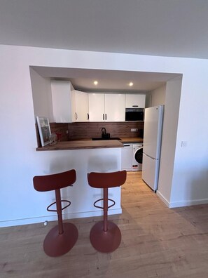 A modern kitchen with white cabinets, a wooden countertop, and a built-in washing machine. - New Listing (Saint-Raphaël)