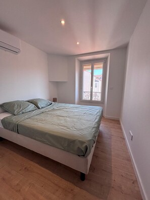 A bedroom with a bed, a window, and a door. - New Listing (Saint-Raphaël)