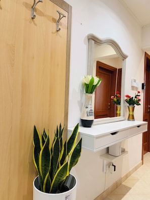 Une salle de bain avec une porte en bois, un lavabo blanc avec un miroir au-dessus, et une plante en pot aux feuilles vertes.